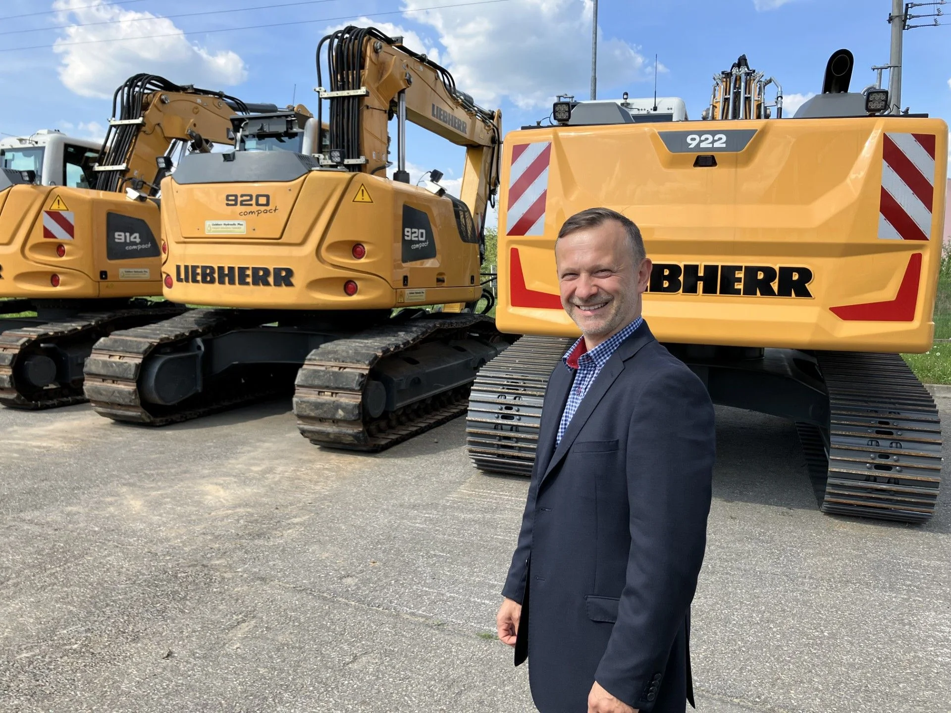 Jaroslav Moravec stojí před stavebními stroji značky Liebherr